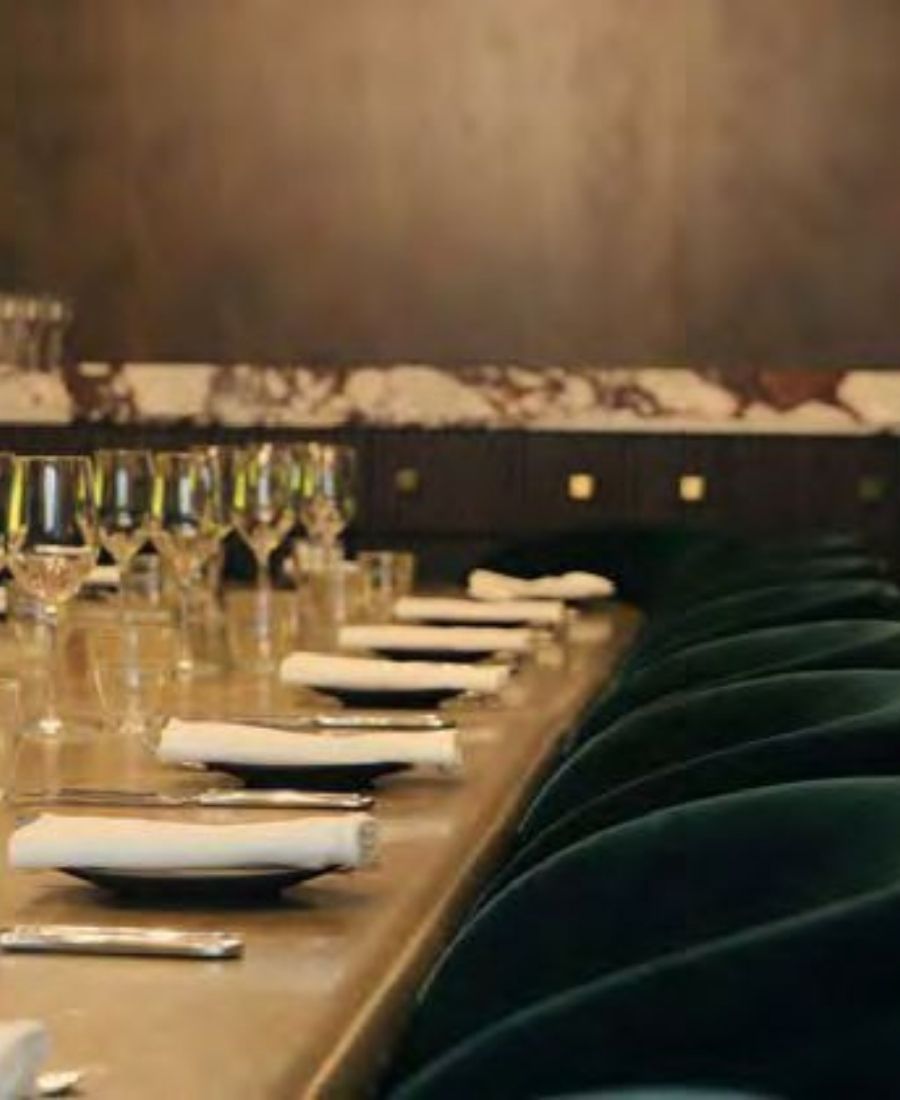 Event space table setting with wine glasses, green velvet chairs and elegant place settings