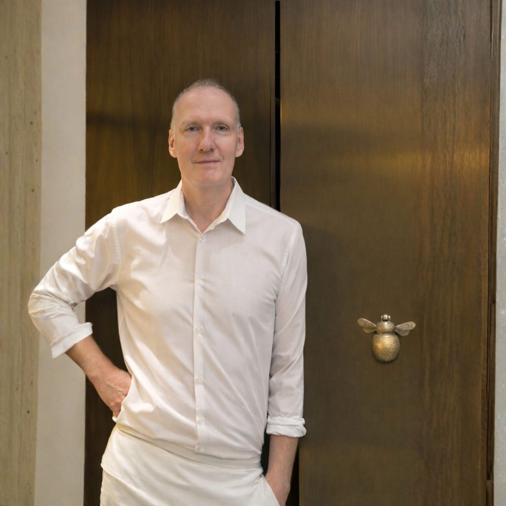 Chef Anthony Demetre standing in Wild Honey restaurant interior wearing white shirt