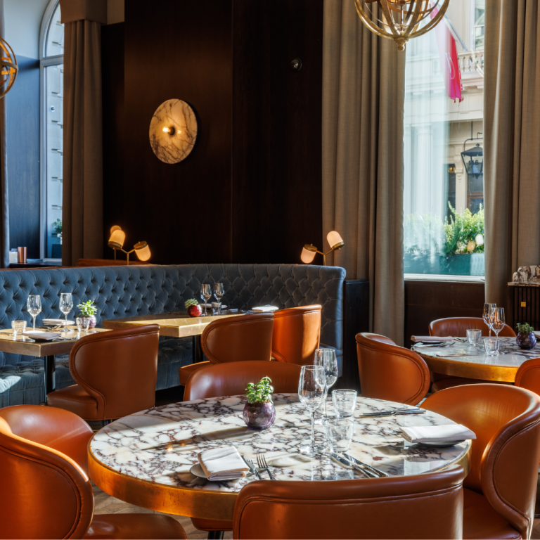 Wild Honey Michelin-starred restaurant interior with marble tables, orange leather chairs and brass lighting fixtures