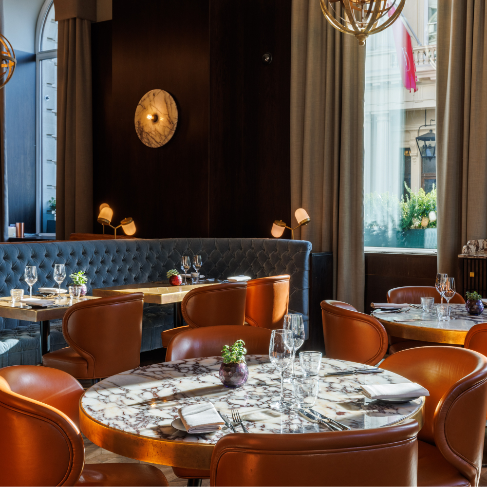 Wild Honey Michelin-starred restaurant interior with marble tables, orange leather chairs and brass lighting fixtures