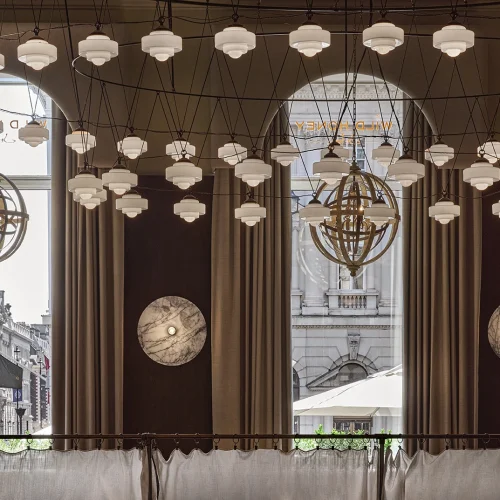 Wild Honey St James philosophy dining space with geometric sphere chandeliers, hexagonal pendant lights, large windows and London architecture views